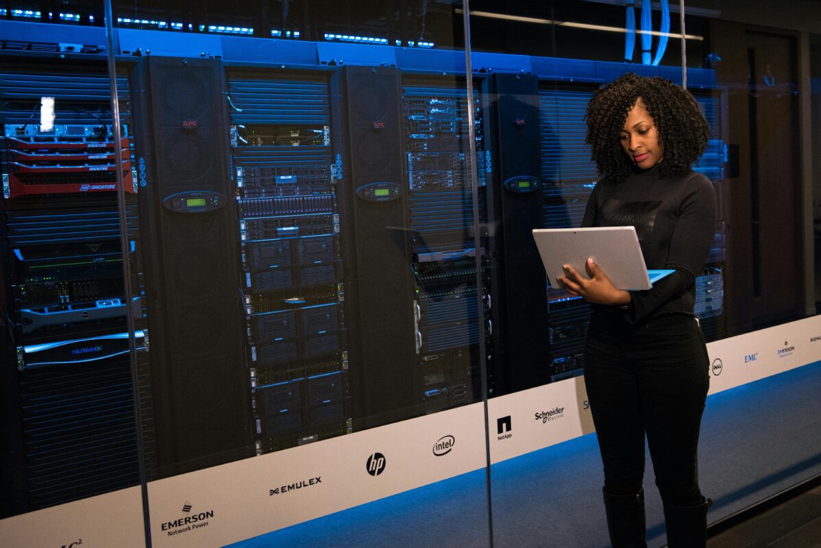 IT professional managing data center rental servers using a laptop in a modern server room